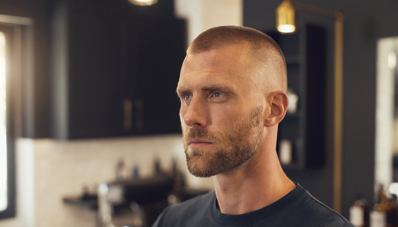 Man with a clean low fade buzz cut photographed in a modern barbershop