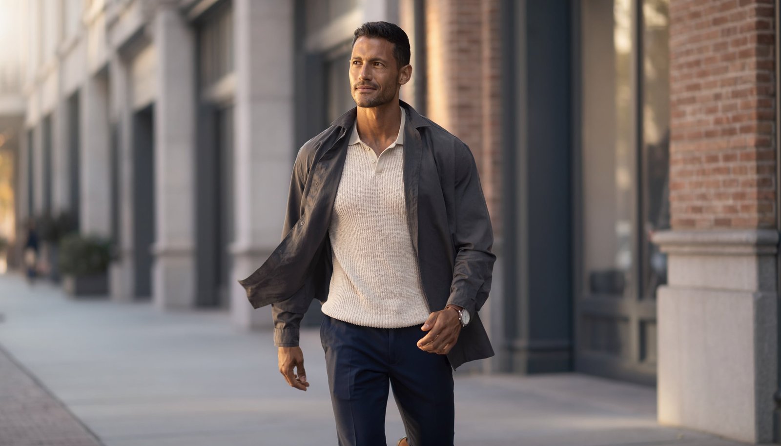 Well-dressed man wearing navy chinos, a knit polo and suede loafers in a modern city setting