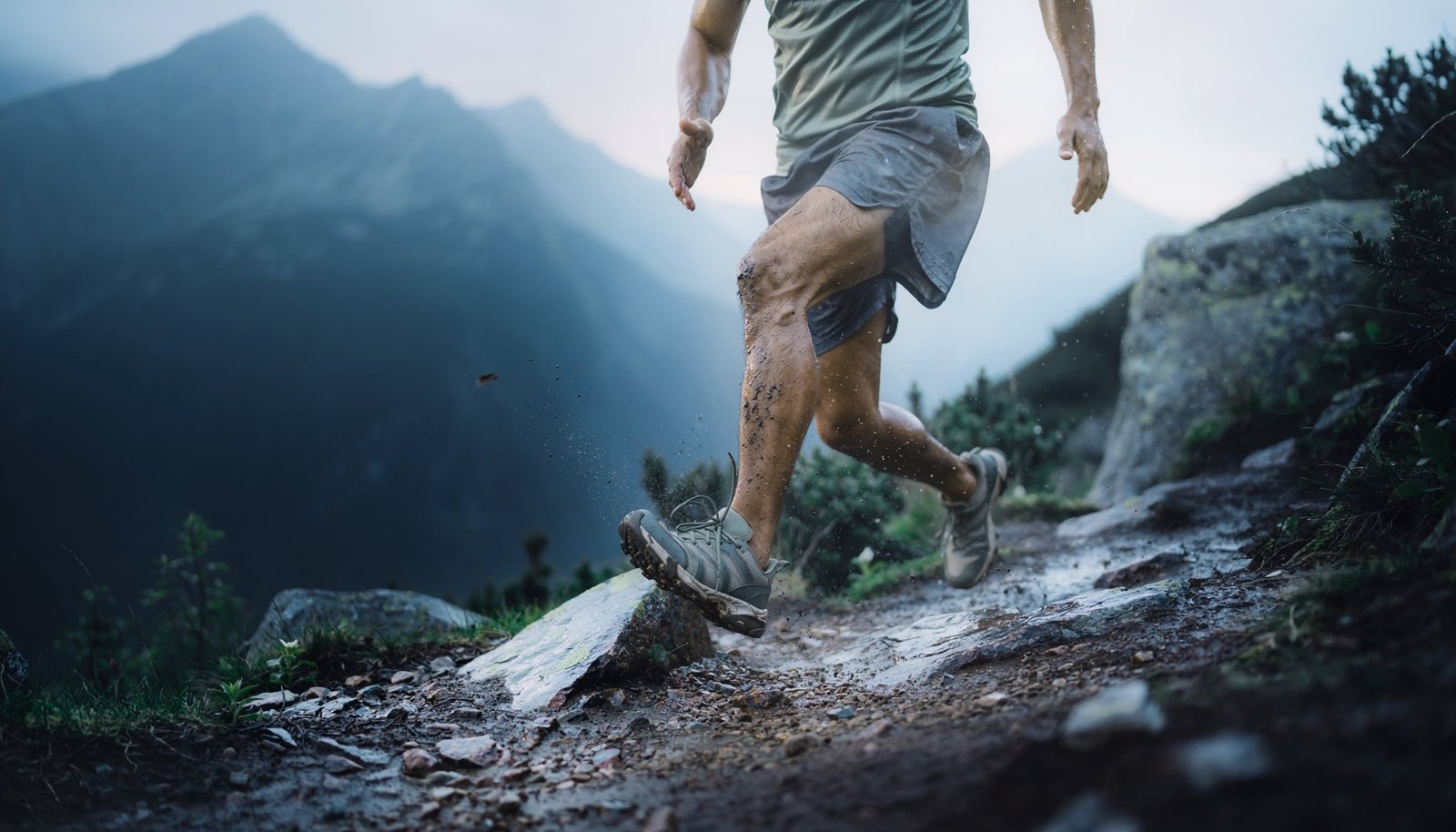 Trail runner crossing wet alpine rock in generic technical trail shoes during early-morning mountain conditions