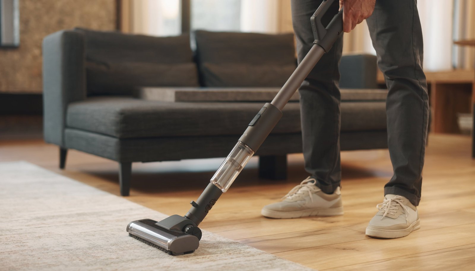 Modern unbranded cordless stick vacuum cleaning hardwood beside a neutral rug in a contemporary living room