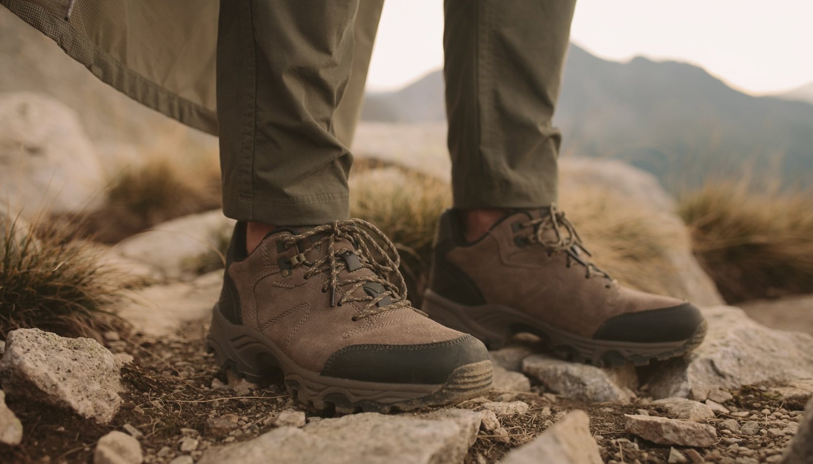Man wearing rugged suede approach shoes on a rocky mountain trail with casual outdoor clothing